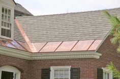 a brick house with a metal roof and shutters