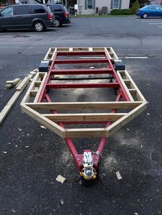 a red trailer sitting on top of a parking lot next to a blue car and buildings