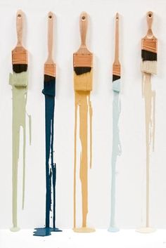 four paint brushes are lined up in a row with one being dipped by the other