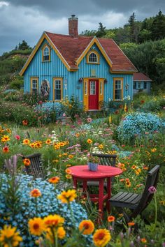 a blue house surrounded by colorful flowers and plants with a red table in the foreground