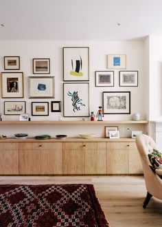 a living room filled with furniture and framed pictures on the wall above it's entertainment center