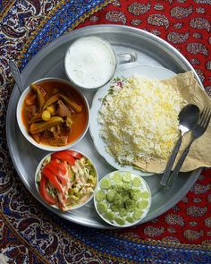 a silver plate topped with rice, meat and veggies next to sauces