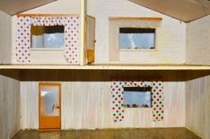 a doll house with two windows and polka dot paper on the walls, in front of a wooden floor