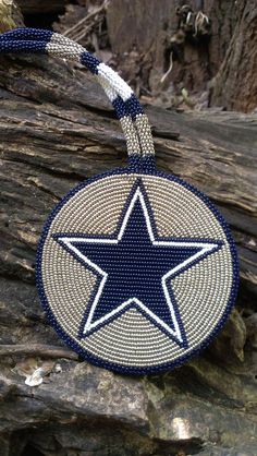 a blue and white beaded star ornament hanging from a tree branch in the woods