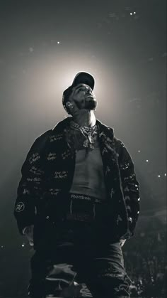 a man standing in front of a crowd wearing a hat and jacket with writing on it