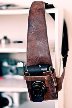 a camera hanging from the side of a wall with a strap around it's neck