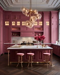 a kitchen with purple cabinets and pink stools next to a marble counter top on a wooden floor