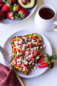 two pieces of toast with strawberries, avocado and feta cheese