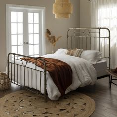 a bedroom with a metal bed frame and white linens on the floor, along with an area rug