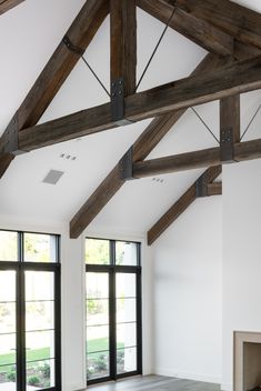 an empty room with large windows and wooden beams