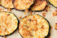 several cooked zucchini slices on a piece of parchment paper with parmesan cheese