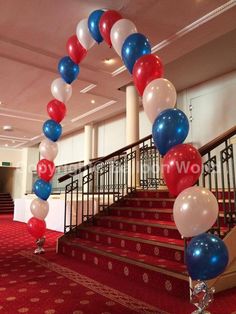 red, white and blue balloons are tied to the stair rail in an elegant hall