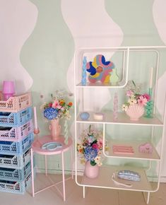 a doll house with pink furniture and flowers on the shelf next to eachother