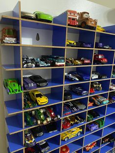 a blue shelf filled with lots of toy cars