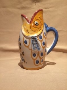 a ceramic mug with a fish design on the front and sides, sitting on a beige background