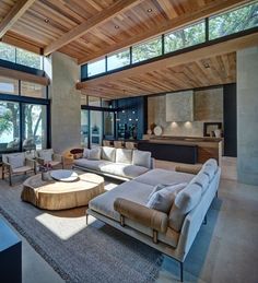 a living room with couches, tables and windows on the side of the wall