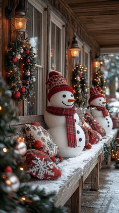 snowmen are lined up on a bench in front of a house decorated for christmas