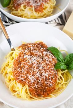 two white bowls filled with spaghetti and sauce