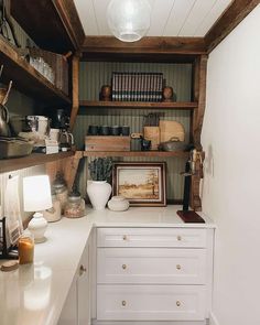 a kitchen with white counter tops and wooden shelves