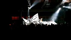 a large group of people standing on top of a stage with lights shining down at them