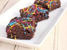 two chocolate brownies with sprinkles on a white plate