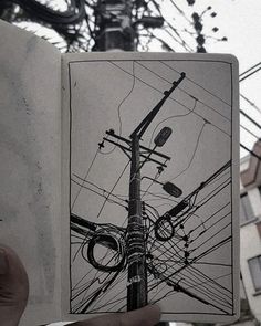 a person holding up an open book with electrical wires in the background