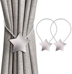 two silver stars hanging from the side of curtains next to a pair of hoop earrings