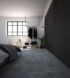 an empty bedroom with clothes hanging on the wall and a bed in the foreground