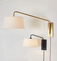 two lamps on the wall next to each other and one light is turned off with a white shade