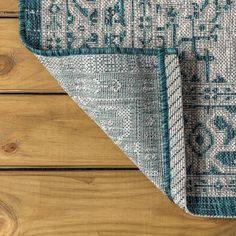 a blue and white rug on top of a wooden floor next to a wood wall