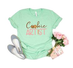 Show off your love for baking with this adorable Cookie Artist shirt! Makes a great gift for cookie bakers and decorators! Want a different design or color? Just let me know and I'll make it happen! FIT & SIZING: * These soft and lightweight Bella-Canvas unisex t-shirts have just the right amount of stretch, and are made in the USA. * Tees are comfortable and flattering for both men and women. * Please see the size chart in the photos to obtain an accurate size. Measure one of your favorite tees Cookie Maker, Baker Shirts, Artist Tees, Artist Shirts, Usa Tee, Shirt Tucked In, Funny Slogans, Make It Happen, Unisex Shirt