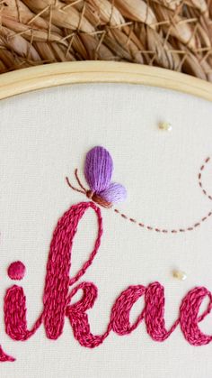 a close up of a embroidery on a piece of cloth with the word lilac