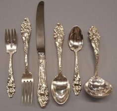 an assortment of silverware including spoons, forks and knives with designs on them