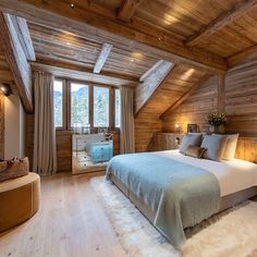 a bedroom with wooden walls and ceiling, white fur rugs on the floor and a large bed in front of a window