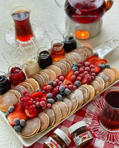 a platter filled with cookies, berries and jams next to a glass of red wine