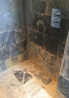 a shower with stone walls and flooring in a bathroom