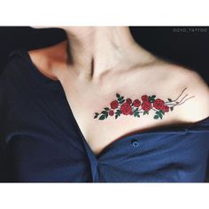 a woman's chest with red roses and green leaves on her left side shoulder