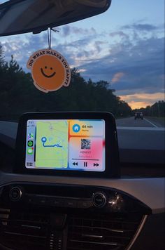 the dashboard of a car with a gps app on it's screen and an orange smiley face hanging from the dash board