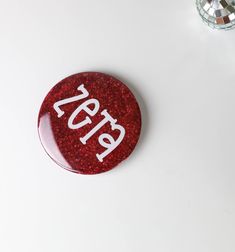 a red button with white letters on it sitting next to a disco ball and mirror