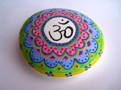 a painted rock with the word om on it, sitting on a white table top