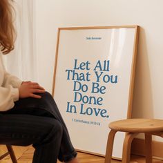 a woman sitting in front of a poster with the words let all that you do be done in love