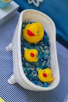 two rubber ducks in a bathtub filled with bubble water and blue bubbles on a table