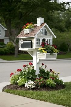 a white bird house with flowers in it