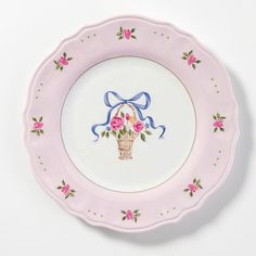 a pink and white plate with flowers on the rim that has a blue ribbon around it