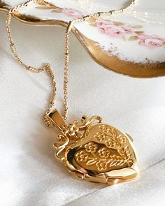 The Jardin Locket Necklace is a vintage inspired heart floral locket.18kt Gold plated silver functioning locket measuring 25mm L x 20mm W x 6.7mm thick. And 9.3 g in weight. The chain is made of gold plated silver measuring 20 inches in length. Gift Locket Pendant Necklace, Flower Pendant Locket Necklace As Gift For Her, Medallion Locket Necklace For Keepsakes, Vintage Locket Jewelry As Gift For Her, Vintage Locket Jewelry As A Gift For Her, Vintage Gold Necklace For Her, Vintage Necklace With Detachable Pendant As Gift, Elegant Pendant Locket Necklace With Vintage Charm, Vintage Round Pendant Charm Necklace