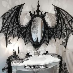 a bathroom decorated in black and white with an intricate dragon wing design on the mirror