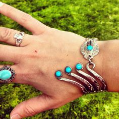 a woman's hand with five different rings on it and turquoise stones in the middle