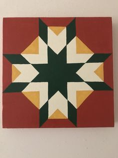 a red and yellow wall hanging with a star design on the bottom, in front of a white wall