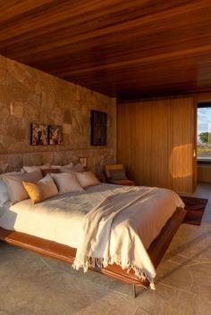 a large bed in a bedroom next to a stone wall and wooden flooring on the walls