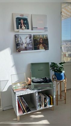 an old record player sits on top of a table in front of a wall with pictures above it